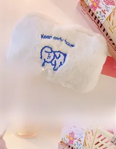 Detail of soft white plush pouch featuring blue cartoon dog embroidery and text