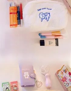 Detail of white plush makeup bag with blue puppy embroidery and cute furry bear keychain