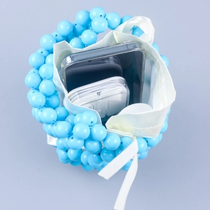 Detail view of woven beaded bucket bag with drawstring liner holding a phone and earbuds