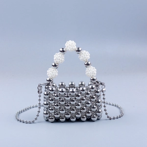 Macro detail of silver beaded crossbody bag with white pearl handle and metal texture