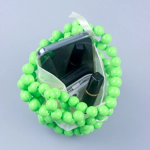 Detail view of green beaded bucket bag showing internal capacity with a white drawstring pouch