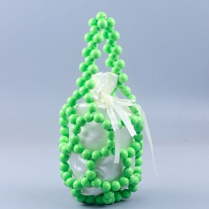 Detail of green beaded bucket bag showing large glossy beads and white satin drawstring pouch