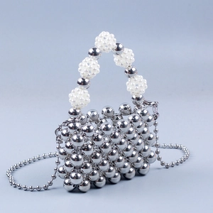 Detail of silver metallic beaded mini bag featuring imitation pearl handle and chain strap