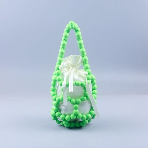 Detail of green beaded bucket bag with hollow woven pattern and white satin drawstring liner