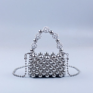 Detail of silver beaded mini handbag with floral handle and long pearl chain strap