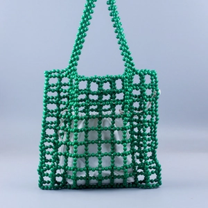 Close-up of handmade green beaded tote bag with hollow mesh and canvas drawstring pouch