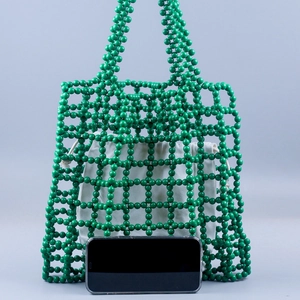Handmade green beaded tote bag with white drawstring liner and size reference phone