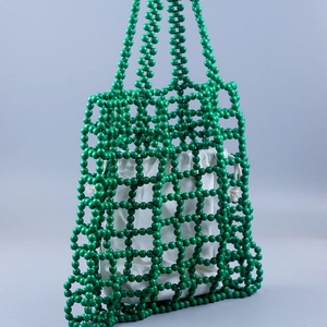 Detail view of handmade green beaded tote bag with hollow mesh design and drawstring liner