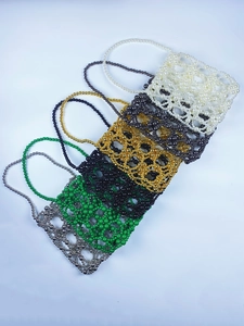 Flat lay of handmade beaded mini bags in six colors including silver and emerald green