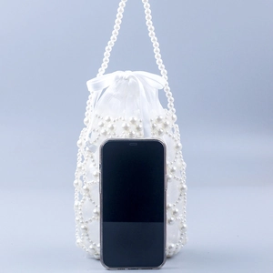 Detail view of woven pearl handbag showing size comparison with a smartphone