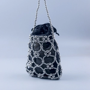 Detailed macro of silver beaded handbag showing hollow mesh and black satin liner