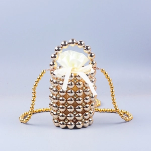 Detail of golden beaded bucket bag with cream satin drawstring lining and pearl handle