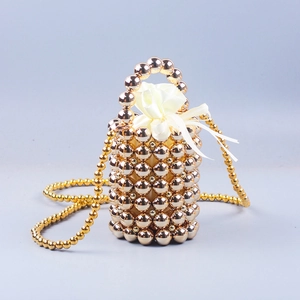 Detailed shot of golden beaded bucket bag with white drawstring lining and metal handle
