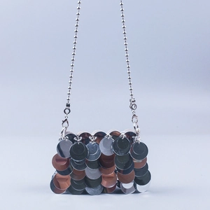 Macro detail of silver sequin scales and bead chain strap on a shimmering crossbody bag