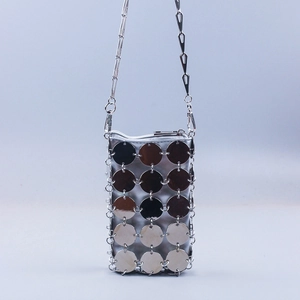Close-up of shiny silver metallic sequin discs and chain strap on a woven crossbody bag
