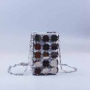 Close-up of shiny silver metal sequins and linked rings on the woven crossbody bag