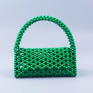 Detailed grid weave of a handmade green beaded handbag with rounded pearl-like texture