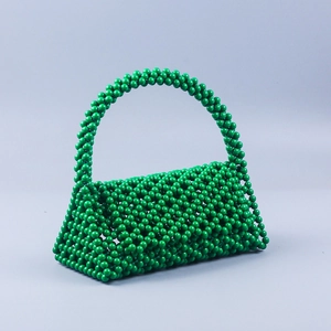 Detailed close-up of handmade green beaded triangle handbag with woven pearl texture