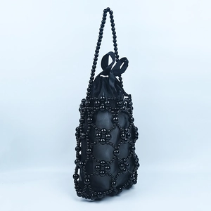 Detail of black handcrafted beaded bucket bag with drawstring liner and ribbon bow