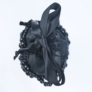 Close-up of black satin drawstring bag with oversized bow and black pearl trim