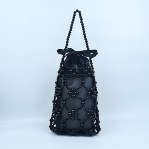Detail showing handcrafted black beaded handbag with a silk drawstring pouch and ribbon