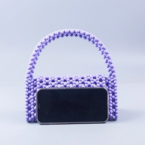 Detail of purple beaded handmade woven handbag with elegant top handle and bead texture
