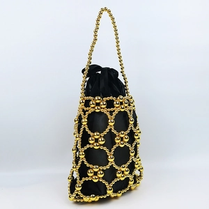 Detail of handmade beaded handbag showing golden hollow mesh and black drawstring lining