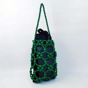 Detail of green beaded bucket handbag featuring geometric hollow weave and black drawstring liner