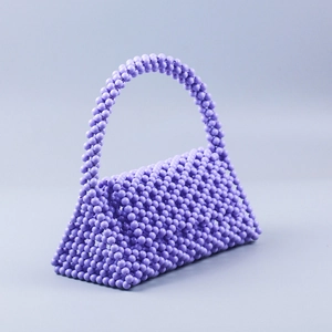 Detail of a handmade purple beaded woven handbag with intricate beadwork and handle