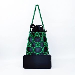 Detail of green beaded handmade handbag featuring a black satin drawstring pouch and smartphone