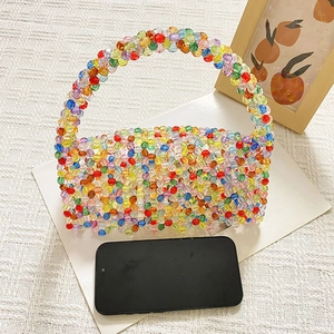Size comparison of colorful handmade beaded handbag next to a smartphone