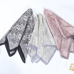 Detailed flat lay of three paisley print square silk scarves in various elegant colors
