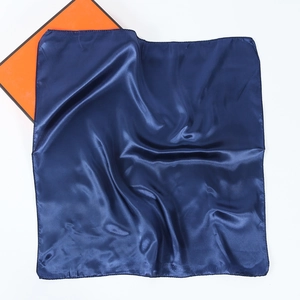 Detail of navy blue silk scarf with satin finish and rolled edge on white background