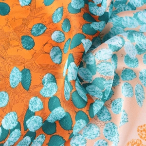 70cm printed silk scarf with orange and cyan leaf pattern shown in close-up folds
