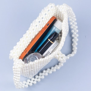 Internal capacity of white acrylic beaded handbag showing phone and cosmetics