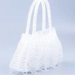 Detailed view of handmade white translucent beaded handbag with woven wave texture