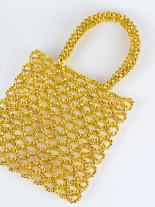 Détail d'un sac à main en perles acryliques dorées tissées main avec motif évidé