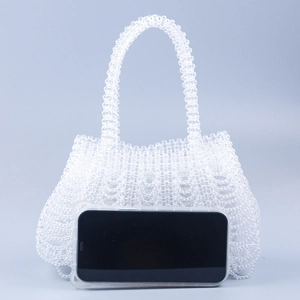 Detail of handcrafted beaded handbag showing intricate weave texture and beaded handle