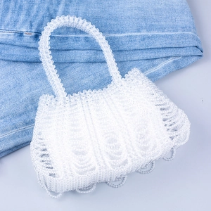 Detailed view of white handmade beaded handbag with transparent wavy woven edges and handle