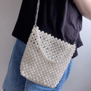 Close-up of handmade white pearl beaded bucket bag with silver metal chain strap