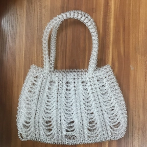 Detail view of transparent beaded handbag with unique wave texture and round handles