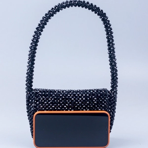 Detailed view of the black beaded evening bag showing compact size next to a smartphone