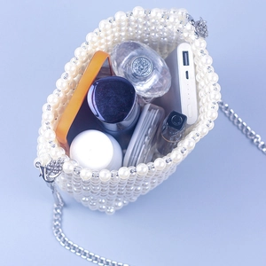 Interior view of white pearl beaded bucket bag showing storage for phone and cosmetics