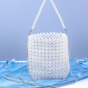 Detail of white acrylic pearl bucket bag with silver chain strap on denim background