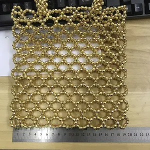 Détail du sac à main en perles dorées montrant une largeur de 19 cm sur une règle
