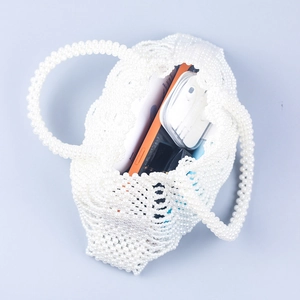 Macro view showing internal capacity of handmade pearl beaded woven handbag with daily items