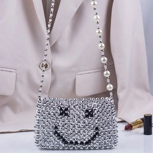 Close-up of handmade silver beaded crossbody bag with smiley face and pearl strap details