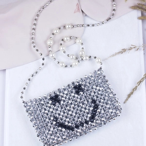 Detail of silver beaded crossbody bag with smiley face and white faux pearl strap