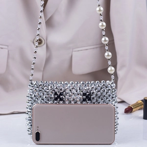 Detailed view of silver beaded crossbody bag with black flower patterns and white pearls