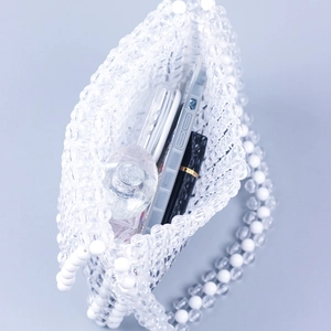 Handmade beaded white acrylic flap handbag showing interior space for phone and makeup